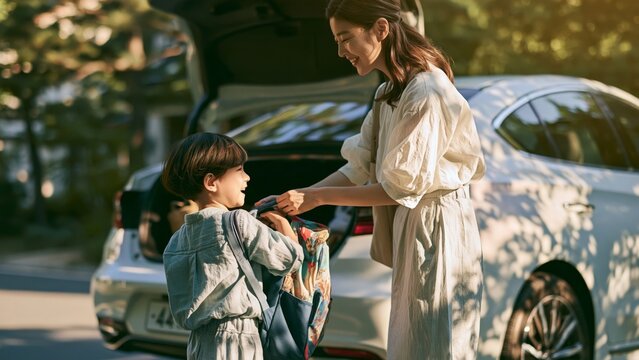 Family - Asian mother and child packing a backpack by the car boot