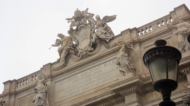 Low Angle View Of Trevi Fountain Top Facade With Papal Coat Of Arms In Rome Italy