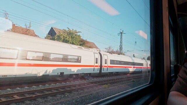 Scenic video footage looking out through the train window at a passing high-speed ICE passenger train carriage of Deutsche Bahn on parallel tracks during a journey in Germany
