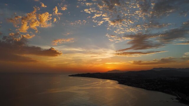 Aerial Drone Footage of Golden Sunset Over Calahonda Coastline, Costa del Sol, Spain, with Scattered Clouds and Mediterranean Sea