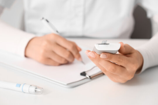 Diabetes management and blood glucose monitoring, doctor or patient recording health data with a glucometer and medical chart in a clinical office