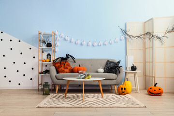 Halloween home decoration, festive living room interior with pumpkins and ghost garland for autumn...
