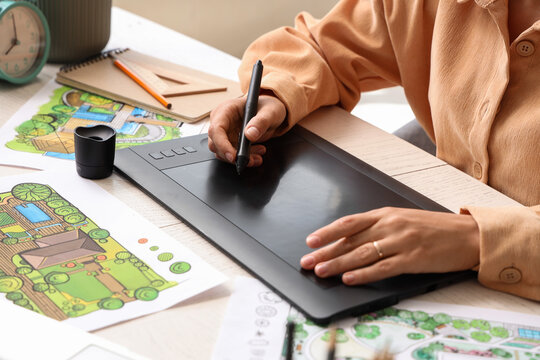 Landscape design and architecture planning, professional architect working on digital tablet with garden blueprints and house sketches at office desk