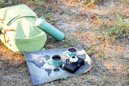 Travel planning and adventure concept, backpack with map and coffee cups on grass for outdoor exploration and wanderlust lifestyle in summer nature