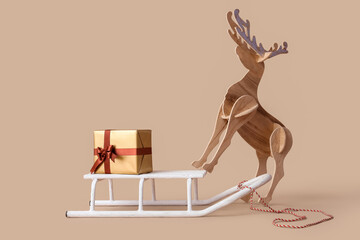 Christmas gift delivery concept, wooden reindeer figurine with gold present on white sled for holiday season celebration and winter festive decoration © Pixel-Shot