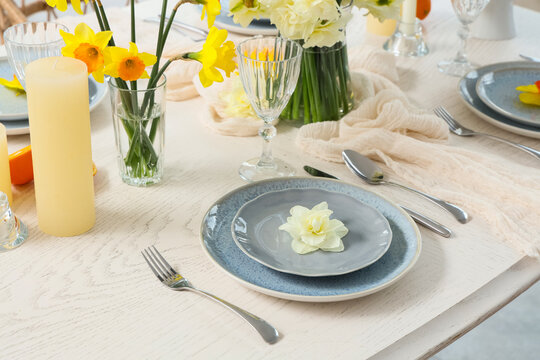 Spring table setting, easter brunch and holiday celebration with fresh daffodils and elegant ceramic plates on a rustic wooden dining table