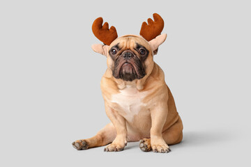 Christmas holiday celebration, french bulldog wearing reindeer antlers headband for festive winter season greeting and pet portrait on grey background © Pixel-Shot