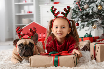 Christmas family joy, little girl and french bulldog wearing reindeer antlers with holiday gifts at home during winter festive season celebration © Pixel-Shot