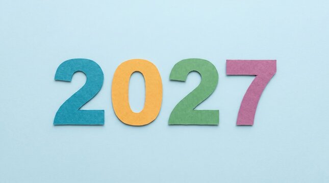 The year 2027 represented by four colorful paper cutout numbers placed in a horizontal row against a solid light blue background, surface texture