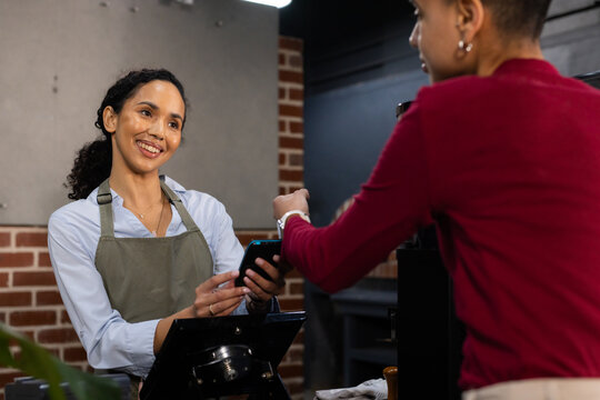 African American women barista and customer processing payment with card reader at coffee counter