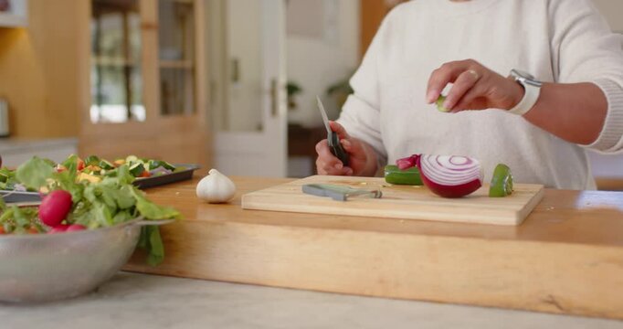 Camera panning Mature African woman dicing veggies at wooden island near POST can preparing meal