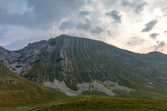 Majestic layered mountain peak rises under dramatic cloudy skies in Zabljak municipality within Durmitor National Park in northern Montenegro showcasing unique rocky geology