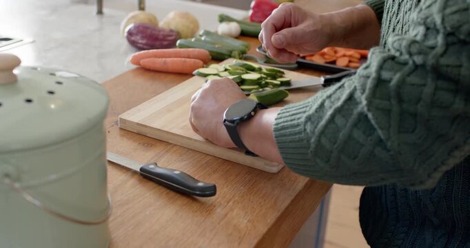 Person's hands are slicing zucchini on countertop for meal prep, placing scraps into POST container