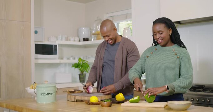 African American couple at kitchen, man holding onion while woman coring pepper to compost for meal