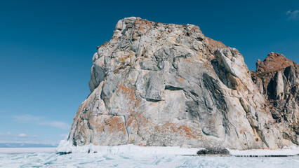 Majestic Shamanka Rock stands proudly over the icy expanses of frozen Lake Baikal near Khuzhir, Irkutsk Oblast, Russia, showing dramatic natural winter scenery under clear blue skies © TravelFlow