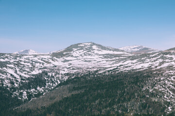 Scenic panoramic landscape of Mount Konzhakovsky Kamen in Sverdlovsk Oblast, Russia, showing snowy alpine slopes, taiga forest, and clear blue sky on a bright day © TravelFlow