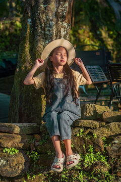 Girl leaning against tree trunk with eyes closed in golden light, Choan Then, Y Ty, Lao Cai, Vietnam
