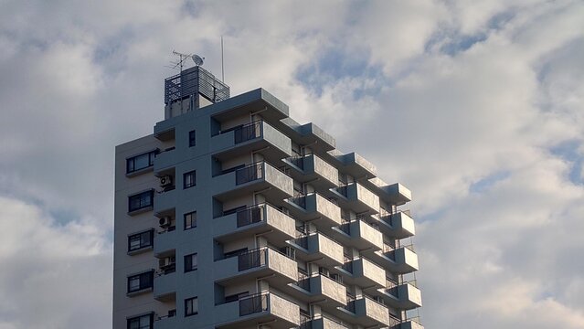青空と雲を背景にした高層マンションの外観