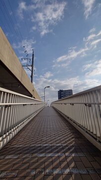 青空の下に続く都市部の歩道橋の風景