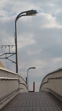 曇り空の下に伸びる歩道橋と街灯