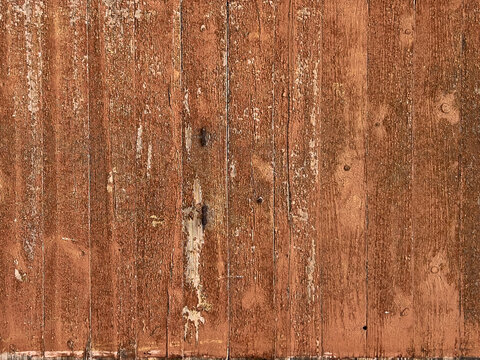 Weathered wooden planks with peeling reddish-brown paint and textured grain detail, close-up background image for rustic decor or design