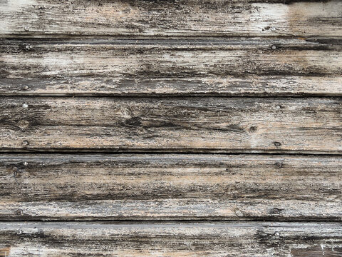 Old weathered wooden planks with heavily textured peeling surface, natural grain and rustic gray brown tones, creating a distressed wood background.