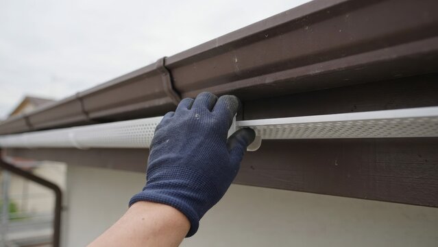Worker installing a gutter guard on a house roof