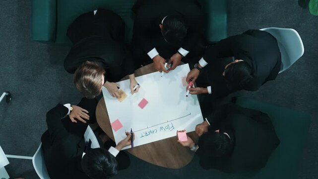 Top down view of business people hands making scrum task board to manage workflow in workplace. Diverse marketing team drawing a line and use colorful stick notes to work on kanban. Directorate.