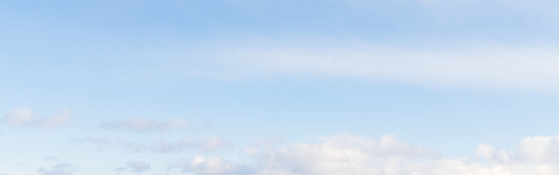 Pale blue winter sky with small soft clouds along the lower edge