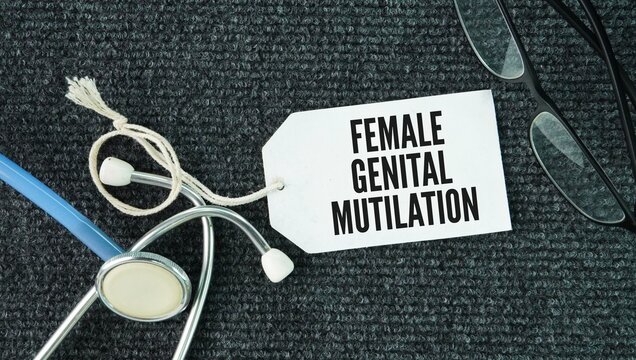 Stethoscope and paper tag with the words Female genital mutilation FGM is the partial or total removal of external female genitalia or other injury to the female genital organs for non-medical reasons