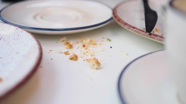 Table after a meal with empty plates and crumbs on the surface