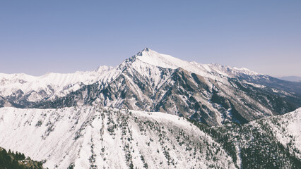 Majestic winter landscape of snowy ridge peaks across the Eastern Sayan mountains in Buryatia, Russia, showcasing frozen alpine ridges, coniferous slopes, and clear panoramic sky © TravelFlow