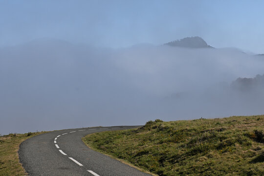 Route asphalt&eacute;e sinueuse menant vers un sommet de montagne dans le brouillard