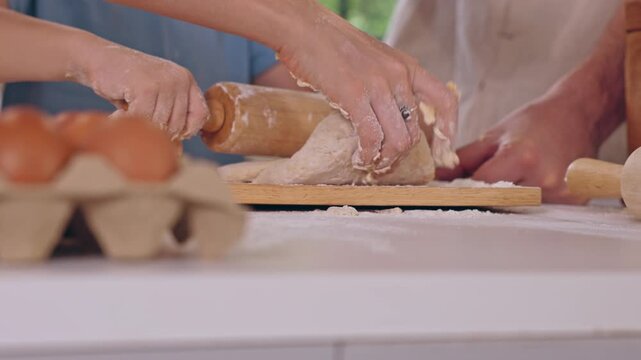 Family baking homemade bread dough in bright kitchen, hands kneading flour and rolling pastry with wooden rolling pin for warm food preparation moment