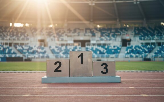 A winners podium on a stadium running track under warm golden sunlight. Competition, victory, and success concept for sports achievement marketing.