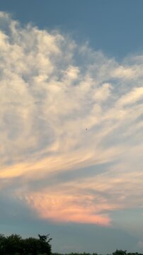 Clouds drifting in a sunset sky over a rural landscape vertical video