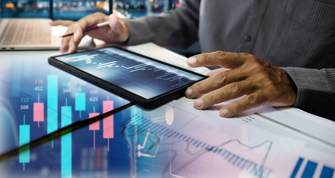 close-up shot, businessman using tablet work on desk in office  analyzing investment graph and chart to make investment plan, double exprosure photo with chart