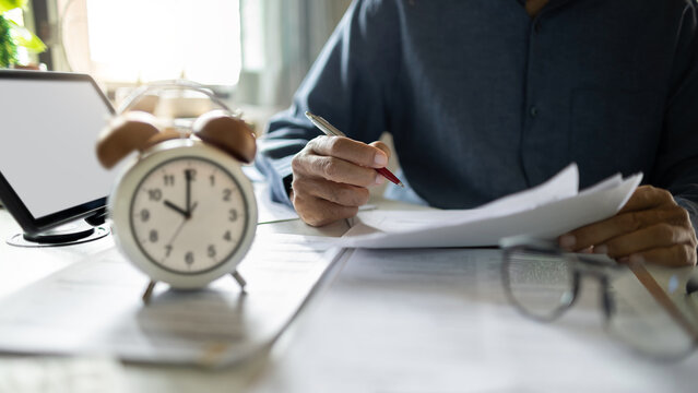 close up shot, asian businessman working on desk with laptop reviewing document. legal expert, professional lawyer reading and checking financial document business contract