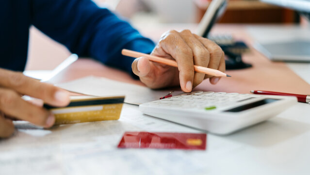 close-up shot, man hand calculate expense from credit card spending before payment credit card debt