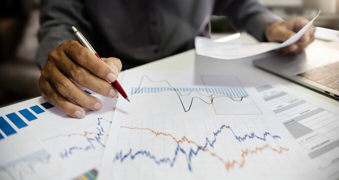 close-up shot, businessman work on desk in office  analyzing investment graph and chart to make investment plan in a future