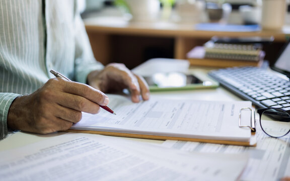 close up shot, businessman hand holding pen checking business contract and loan from before sign for apply business loan to start new business online, E-commerce concept