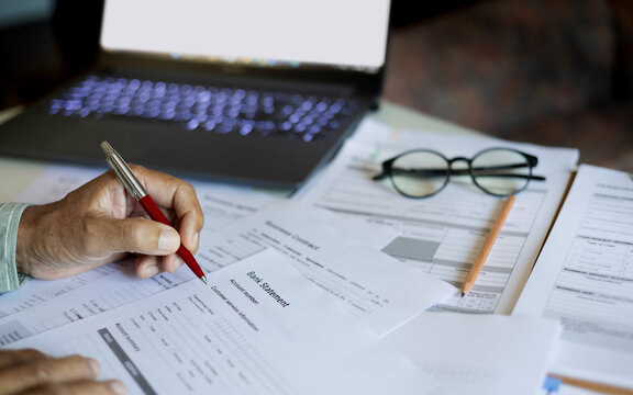 close up shot, man hand checking bank statement and business document to apply for a business startup loan, doing online business, E-commerce business