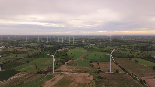 Aerial view of wind turbine spinning over rural countryside in early morning for alternative energy