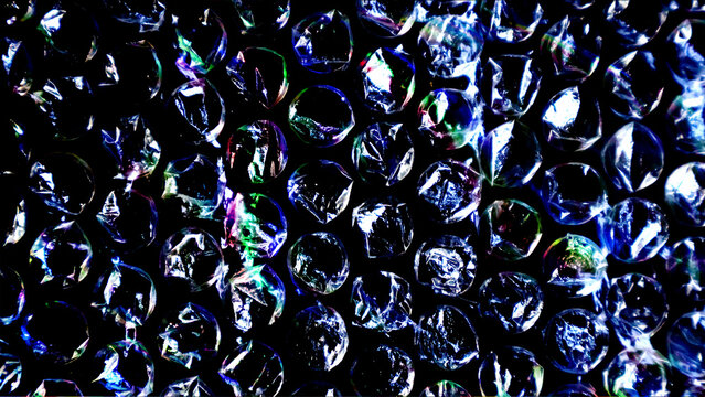 Abstract iridescent bubble wrap texture with colorful reflections on black background for packaging design.