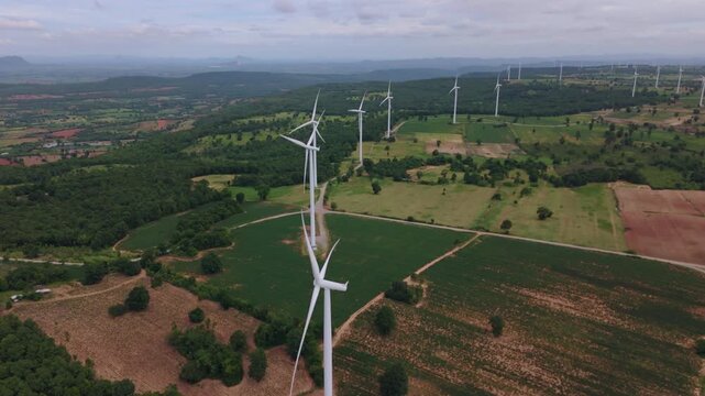 Drone view of wind turbine row over forest and hills for sustainable green energy
