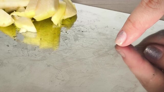 Close-up of scratches and cutting marks on a stainless steel kitchen cutting board, showing visible signs of everyday use.