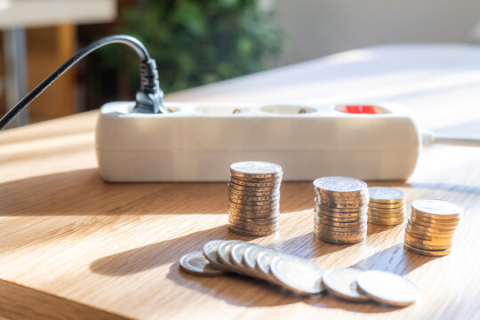 Coins representing money and cost increasing next to a power strip with a plug connected, symbolizing rising electricity bills, energy efficiency, and expenses for power consumption in a household
