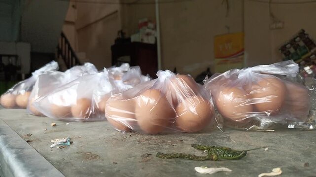 Plastic-wrapped chicken eggs on a glass table against a dark background.