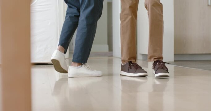 As feet are approaching, white and brown sneakers are weaving on shiny floor in hallway