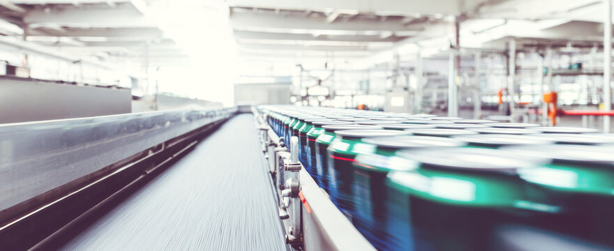 Cans moving on conveyor belt in beverage factory, production line with blur effect showing speed